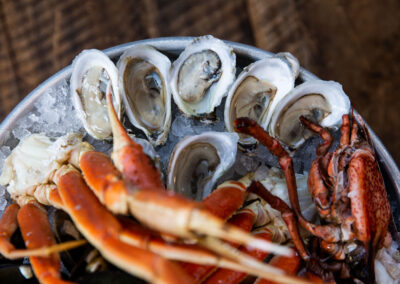 Top layer of a Seafood Tower with focus on raw oysters over ice and piled high with whole crab and crab leg clusters.